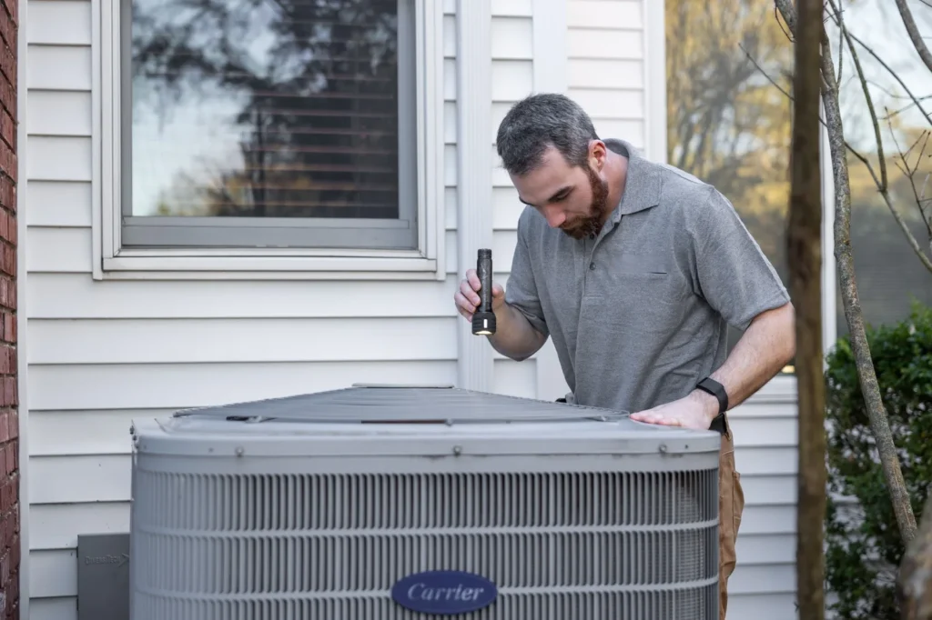 Technician inspecting an outdoor air conditioning unit during HVAC maintenance