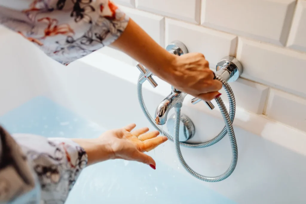 Person checking water temperature from a bathtub faucet
